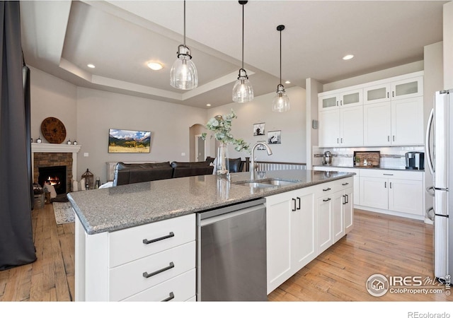 kitchen with backsplash, a sink, light wood-style floors, hanging light fixtures, and appliances with stainless steel finishes