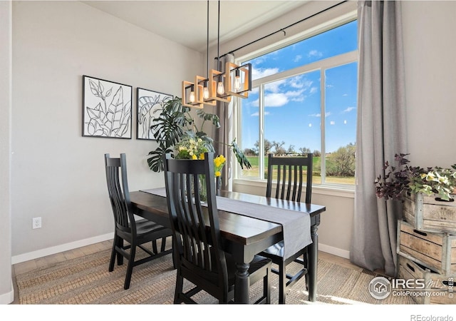 dining area featuring wood finished floors, baseboards, and an inviting chandelier