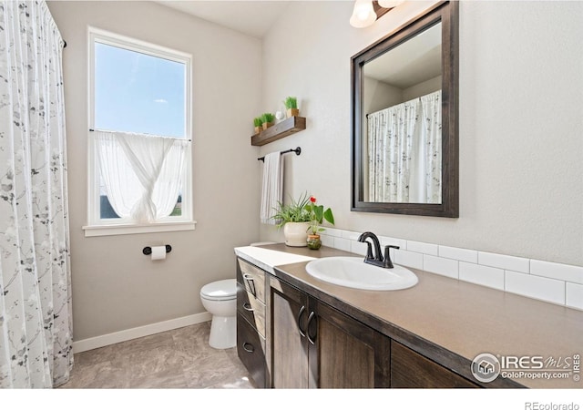 full bathroom featuring toilet, baseboards, vanity, and a healthy amount of sunlight