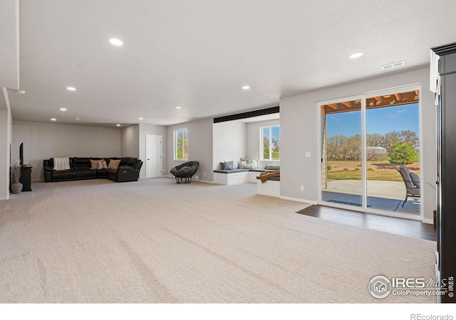 carpeted living area featuring baseboards, visible vents, and recessed lighting