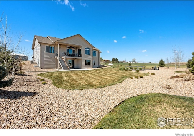 rear view of property featuring stairway and a lawn