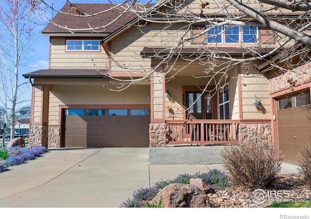 view of front of property with an attached garage, driveway, a porch, and stone siding