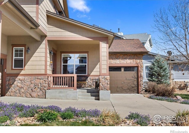 exterior space with a garage, a porch, stone siding, and concrete driveway