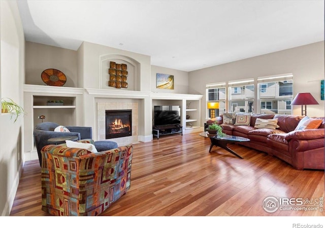 living area with built in features, light wood-style floors, and a fireplace