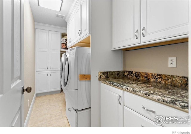 laundry area featuring baseboards, visible vents, independent washer and dryer, cabinet space, and light tile patterned floors