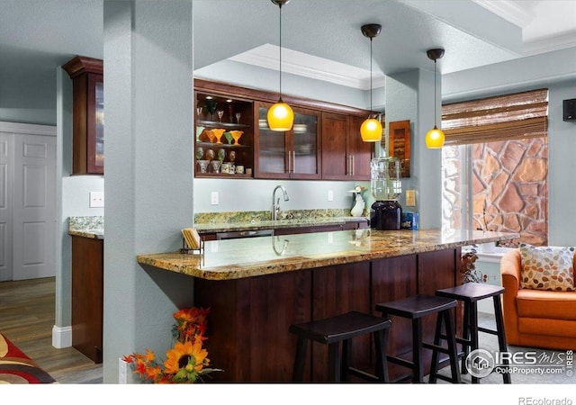 bar with wood finished floors, decorative light fixtures, a sink, and crown molding