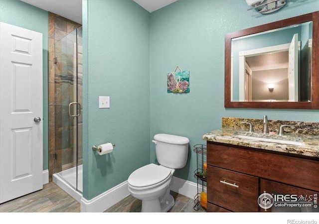 bathroom featuring a shower stall, baseboards, toilet, and wood finished floors