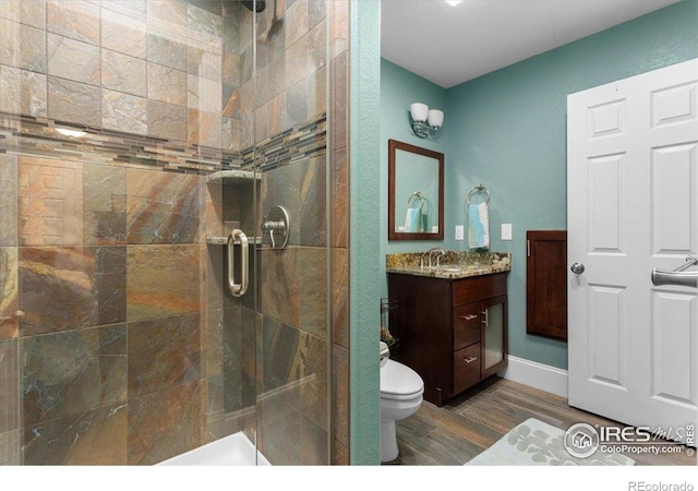 bathroom with vanity, wood finished floors, a shower stall, and toilet