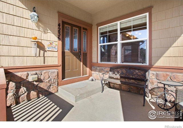 doorway to property with stone siding and covered porch