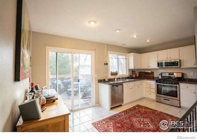 1504 Washington Ave, Louisville, CO 80027 - kitchen with light tile patterned floors, white cabinets, a sink, and appliances with stainless steel finishes