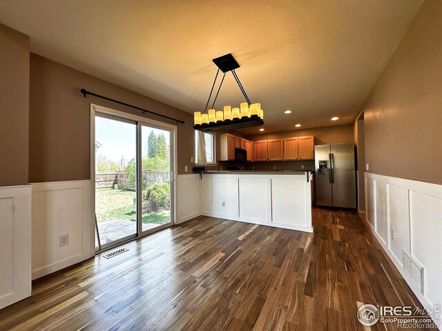 6502 Carmichael St, Fort Collins, CO 80528 - kitchen with a wainscoted wall, stainless steel fridge with ice dispenser, visible vents, black microwave, and a peninsula