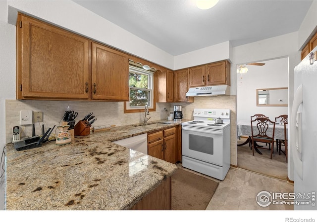 2417 15th Ave, Longmont, CO 80503 - kitchen with under cabinet range hood, a sink, white appliances, light stone countertops, and brown cabinetry