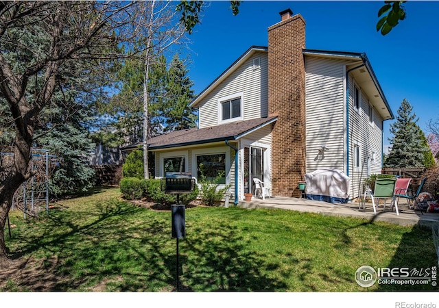2417 15th Ave, Longmont, CO 80503 - back of property featuring a lawn, a chimney, and a patio area