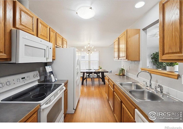1114 Berwick Ct, Fort Collins, CO 80524 - kitchen with white appliances, a sink, a chandelier, light wood finished floors, and brown cabinets