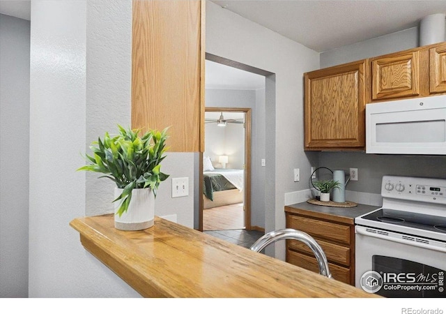 1114 Berwick Ct, Fort Collins, CO 80524 - kitchen with white appliances, brown cabinets, a ceiling fan, and tile patterned flooring