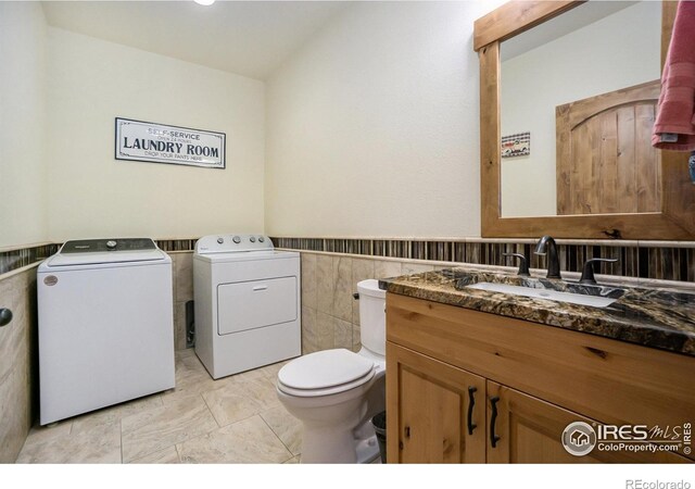 223 Kings Canyon Rd, Bellvue, CO 80512 - half bath featuring washer and clothes dryer, toilet, tile walls, vanity, and wainscoting