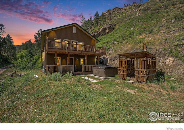 223 Kings Canyon Rd, Bellvue, CO 80512 - back of property at dusk featuring a hot tub, a wooden deck, and a lawn