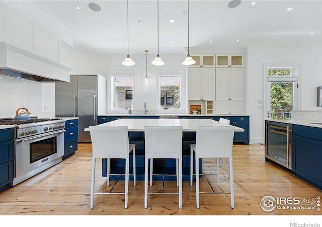 563 Arapahoe Ave, Boulder, CO 80302 - kitchen featuring blue cabinetry, premium appliances, wine cooler, custom range hood, and recessed lighting