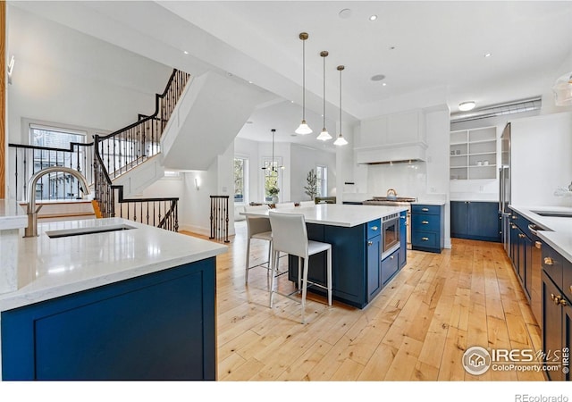 563 Arapahoe Ave, Boulder, CO 80302 - kitchen with blue cabinets, a sink, light wood-style flooring, a center island, and recessed lighting