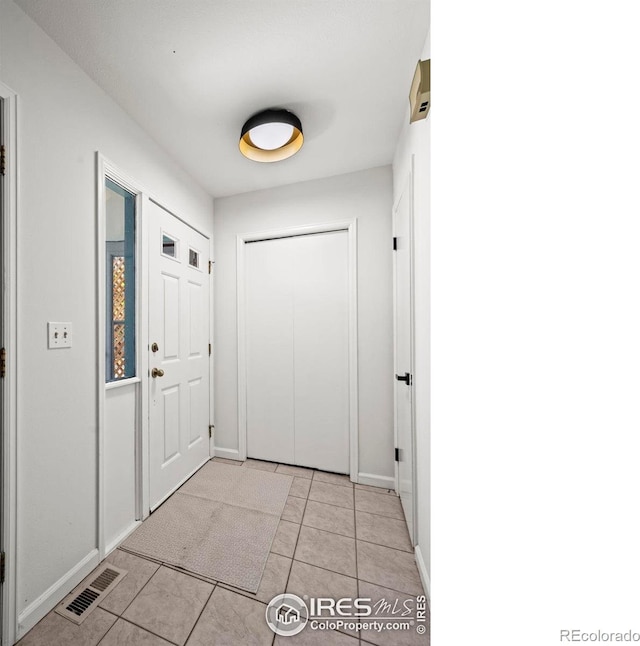 doorway to outside featuring baseboards, visible vents, and light tile patterned floors