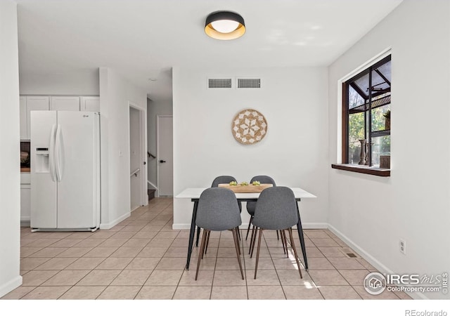 dining room with light tile patterned flooring, visible vents, baseboards, and stairs