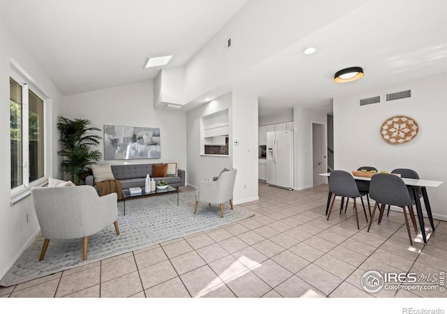 living area featuring lofted ceiling, visible vents, baseboards, and light tile patterned floors