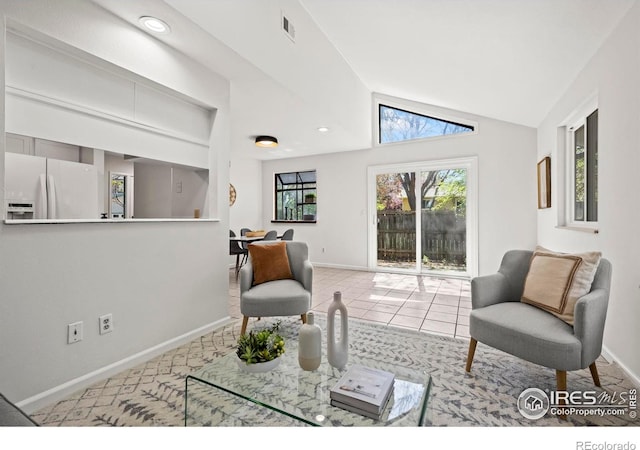 living area with vaulted ceiling, visible vents, and baseboards