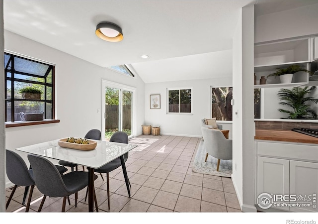 dining space featuring lofted ceiling, baseboards, and light tile patterned floors