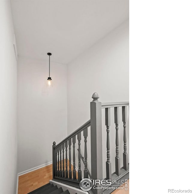 staircase featuring baseboards and wood finished floors