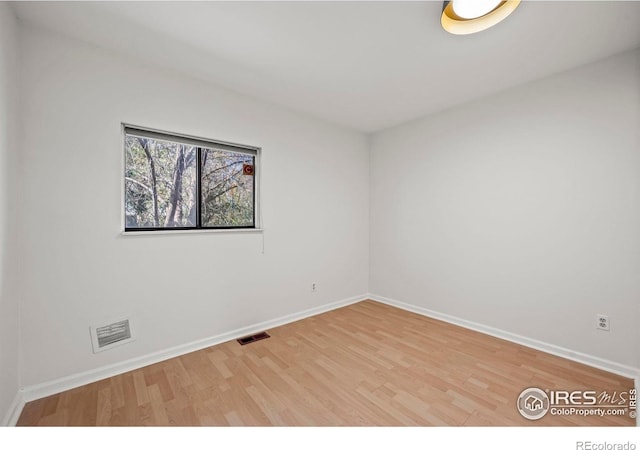 empty room with baseboards, wood finished floors, and visible vents