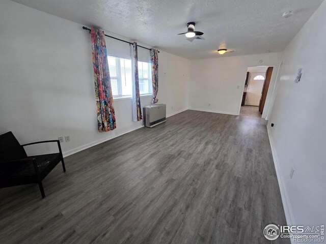 409 N 4th Ave, Sterling, CO 80751 - unfurnished living room featuring a ceiling fan, dark wood finished floors, baseboards, and a textured ceiling