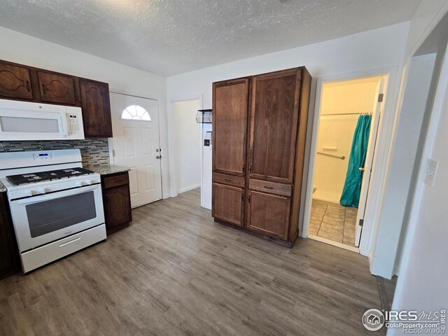 409 N 4th Ave, Sterling, CO 80751 - kitchen featuring white appliances, wood finished floors, a textured ceiling, decorative backsplash, and dark brown cabinets