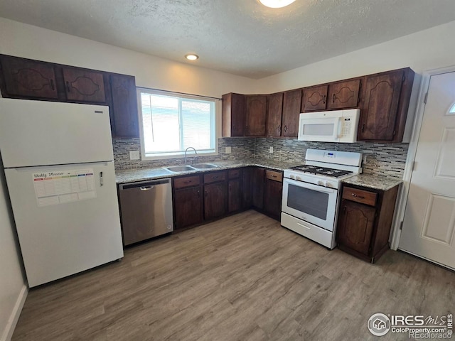 409 N 4th Ave, Sterling, CO 80751 - kitchen featuring white appliances, a sink, light wood finished floors, backsplash, and a textured ceiling
