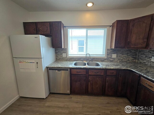 409 N 4th Ave, Sterling, CO 80751 - kitchen with stainless steel dishwasher, freestanding refrigerator, a sink, tasteful backsplash, and light wood-style floors