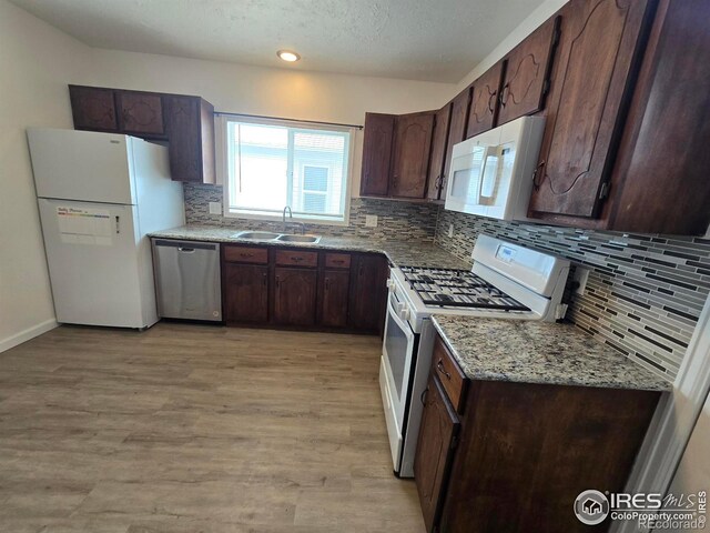 409 N 4th Ave, Sterling, CO 80751 - kitchen with white appliances, a sink, tasteful backsplash, light wood-type flooring, and dark brown cabinets