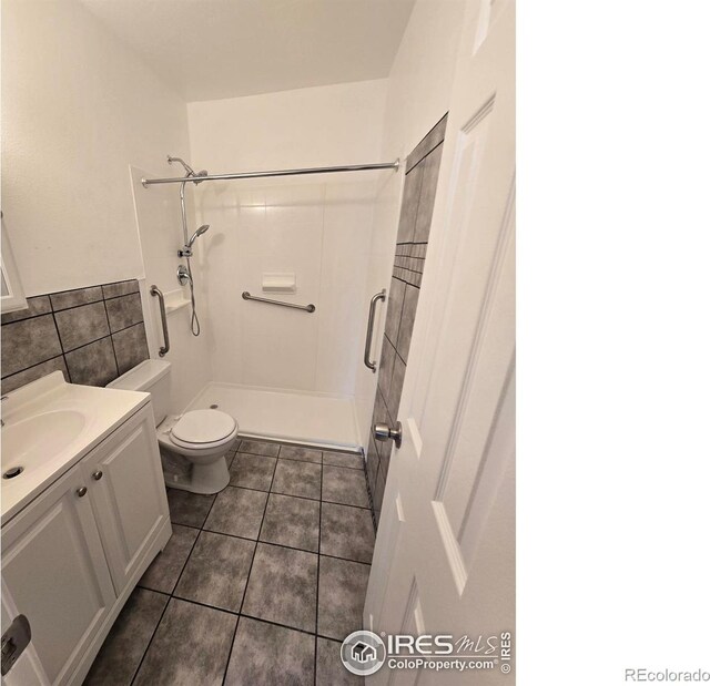 409 N 4th Ave, Sterling, CO 80751 - full bath with a shower stall, toilet, tile patterned floors, vanity, and tile walls