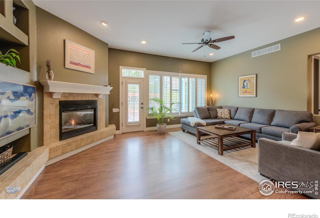 living area featuring recessed lighting, a tile fireplace, wood finished floors, visible vents, and a ceiling fan