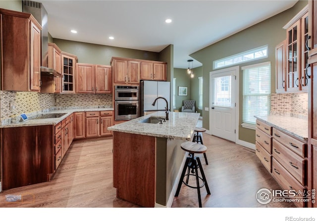 kitchen with light wood finished floors, a sink, tasteful backsplash, freestanding refrigerator, and double oven