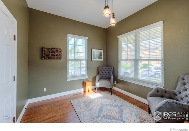 living area with baseboards, wood finished floors, and visible vents