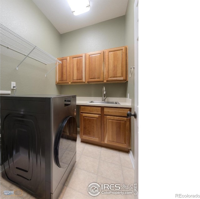 laundry area featuring washing machine and clothes dryer, cabinet space, a sink, and light tile patterned floors