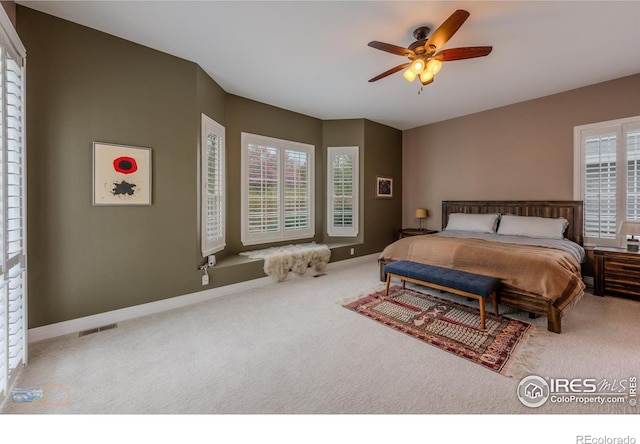 carpeted bedroom featuring baseboards, visible vents, ceiling fan, and multiple windows