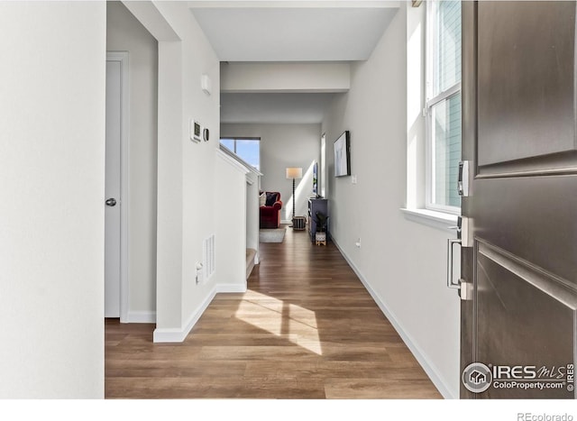 foyer with stairway, baseboards, wood finished floors, and visible vents