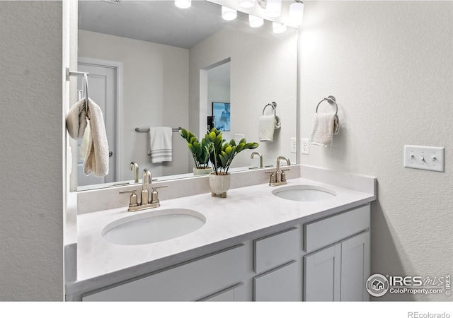 full bathroom featuring a textured wall, a sink, and double vanity