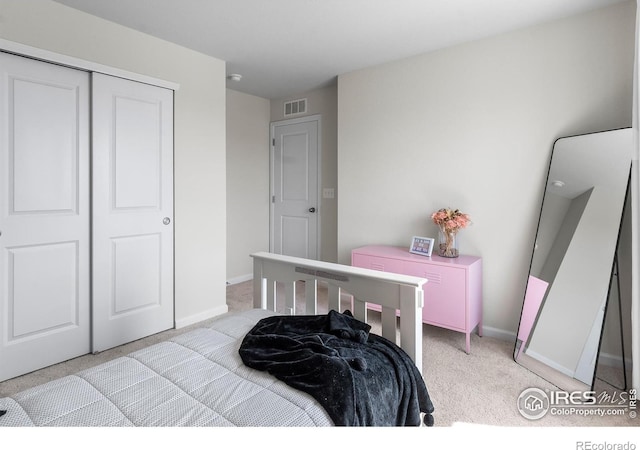 bedroom featuring a closet, baseboards, visible vents, and light colored carpet