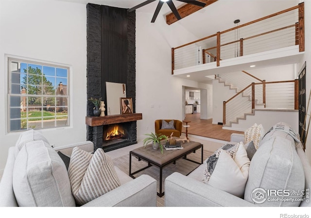 7102 S Harrison Ct, Centennial, CO 80122 - living room featuring high vaulted ceiling, stairway, a warm lit fireplace, beam ceiling, and a ceiling fan