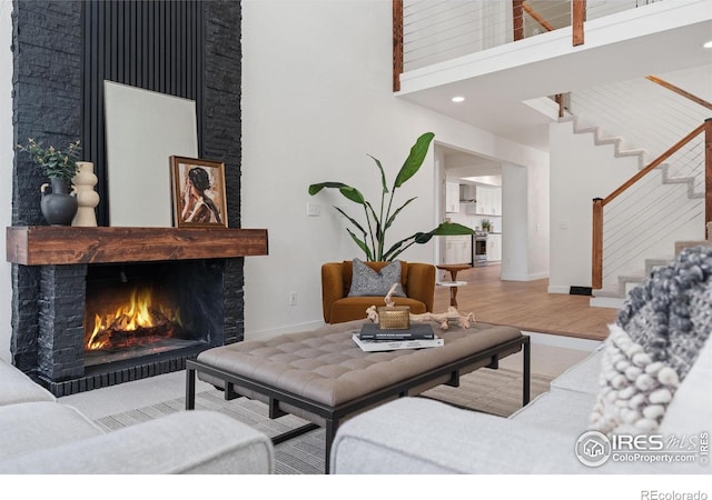 7102 S Harrison Ct, Centennial, CO 80122 - living room featuring a towering ceiling, wood finished floors, baseboards, a lit fireplace, and stairway