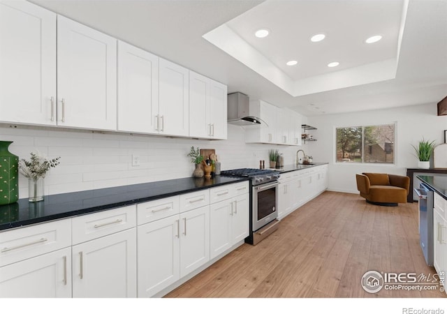 7102 S Harrison Ct, Centennial, CO 80122 - kitchen with stainless steel appliances, wall chimney range hood, recessed lighting, white cabinetry, and light wood-type flooring