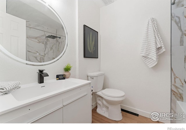 7102 S Harrison Ct, Centennial, CO 80122 - full bathroom with vanity, a marble finish shower, toilet, wood finished floors, and baseboards