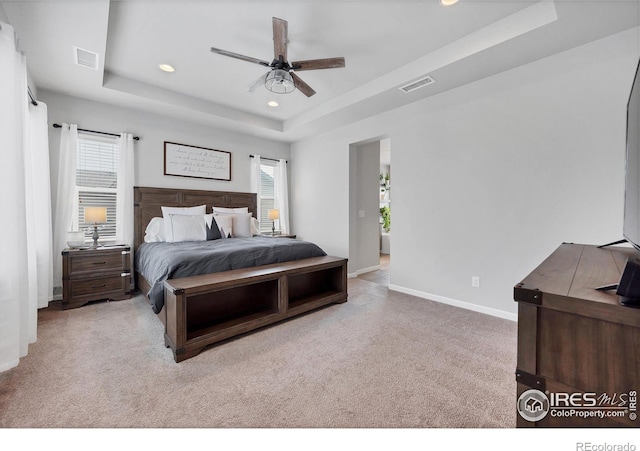 carpeted bedroom featuring baseboards, visible vents, recessed lighting, and a raised ceiling