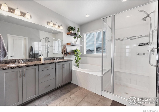 full bathroom featuring a sink, double vanity, tile patterned flooring, a shower stall, and a garden tub